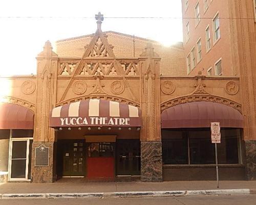 Gevel van het art-decotheater Yucca Theatre met sierlijke details en gestreepte luifels boven de ingangen