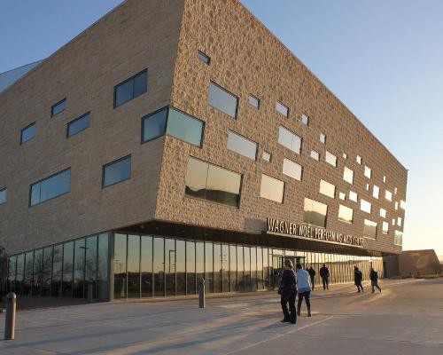 Modern gebouw met een gevel van bruine baksteen en onregelmatige vensters, met de naam Wagner Noël Performing Arts Center