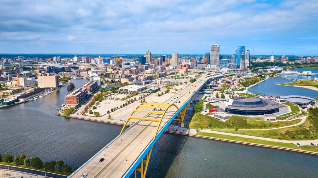 Luchtfoto van de gele boogbrug Hoan Bridge die naar de skyline van Milwaukee leidt, met het water van het meer aan weerszijden