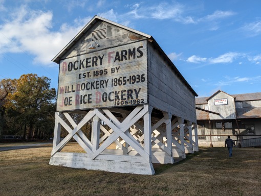 Verweerde witte schuur met het opschrift Dockery Farms opgericht in 1895 op houten palen in Mississippi