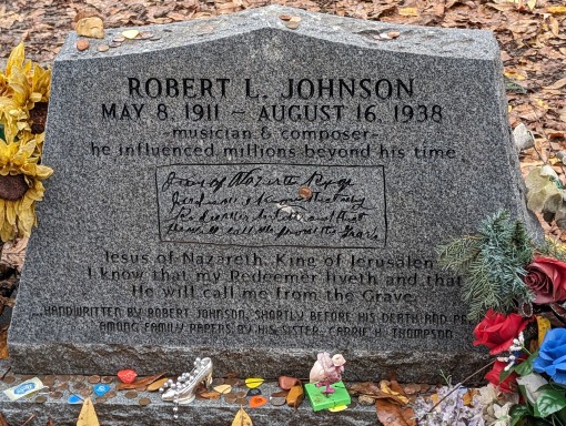 Grijze grafsteen met de naam Robert L. Johnson en een lange grafinscriptie, versierd met bloemen en kleine aandenkens