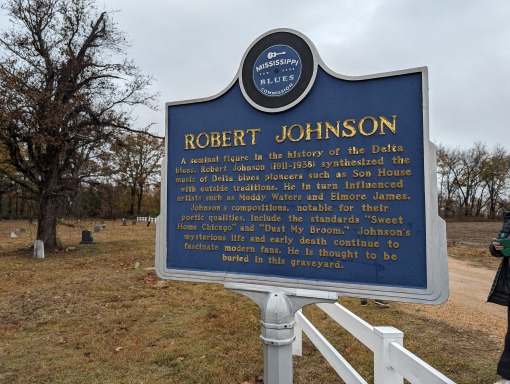 Blauw informatiebord van de Mississippi Blues Trail met tekst over het leven van bluesmuzikant Robert Johnson bij een begraafplaats
