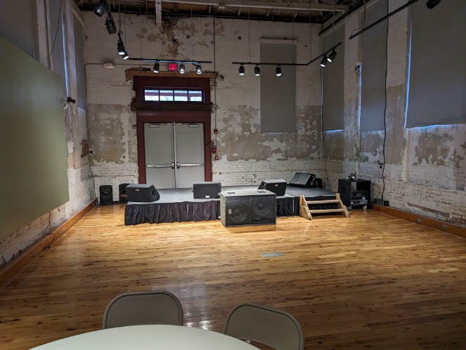 Verlaten houten dansvloer met een klein podium vol geluidsapparatuur in een oude bakstenen zaal in Mississippi