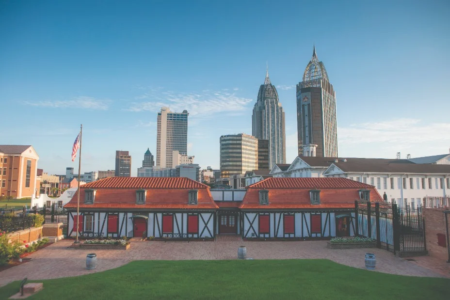 Koloniaal fort met roodwitte gebouwen en Amerikaanse vlag voor de moderne skyline van Mobile, Alabama