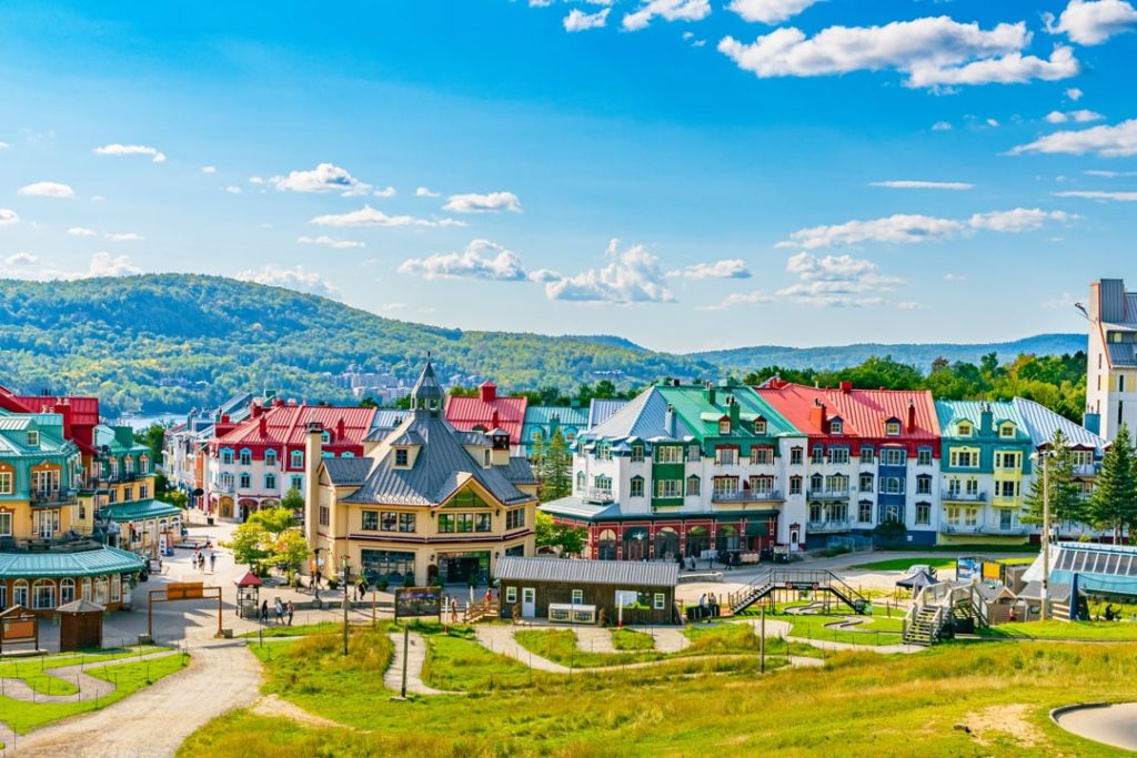 Voetgangersplein met bonte gekleurde daken en gevels in het bergdorp Mont-Tremblant met beboste heuvels op de achtergrond