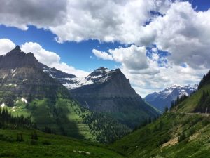 Groen dal tussen ruige bergtoppen onder een dramatische wolkenlucht in Glacier National Park