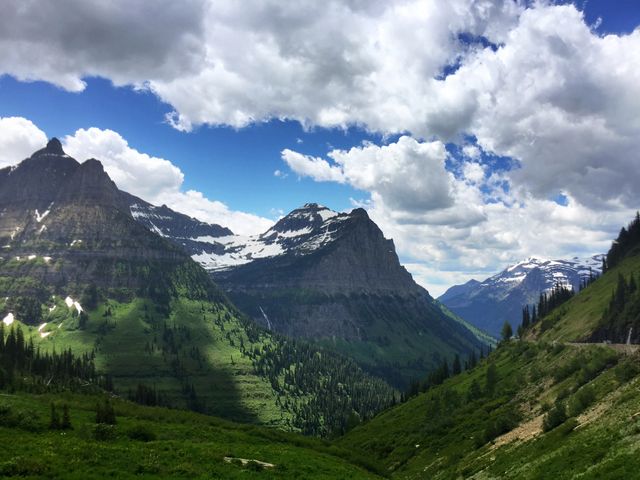Groen dal tussen ruige bergtoppen onder een dramatische wolkenlucht in Glacier National Park