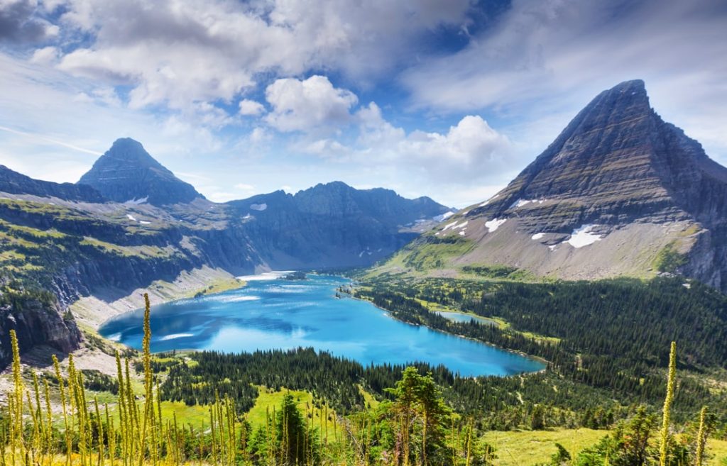 Turquoise Hidden Lake ligt tussen scherpe bergtoppen met groene valleien in Glacier National Park