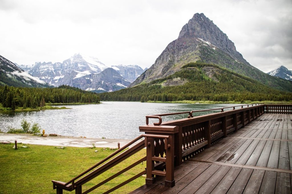 Houten terras met balkon kijkt uit over een meer met een markante bergpiek in Glacier National Park in Montana