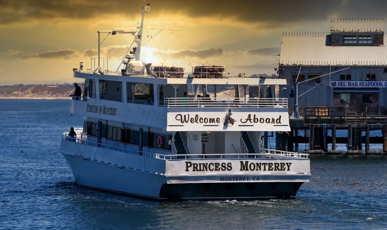 De witte excursieboot Princess Monterey vaart bij zonsondergang terug naar de pier in Monterey