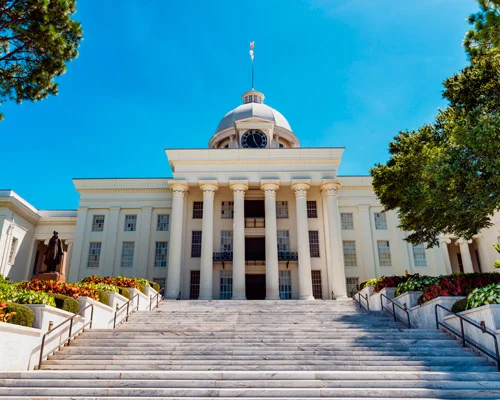 Zuilengalerij en gouden koepel met klok van het Alabama State Capitol in Montgomery, gezien vanaf de brede trap met een standbeeld ernaast