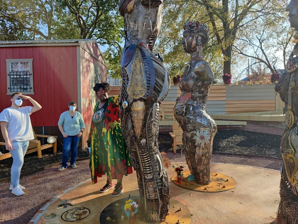 Bezoekers bekijken grote metalen kunstwerken van menselijke figuren in een buitentuin in Montgomery