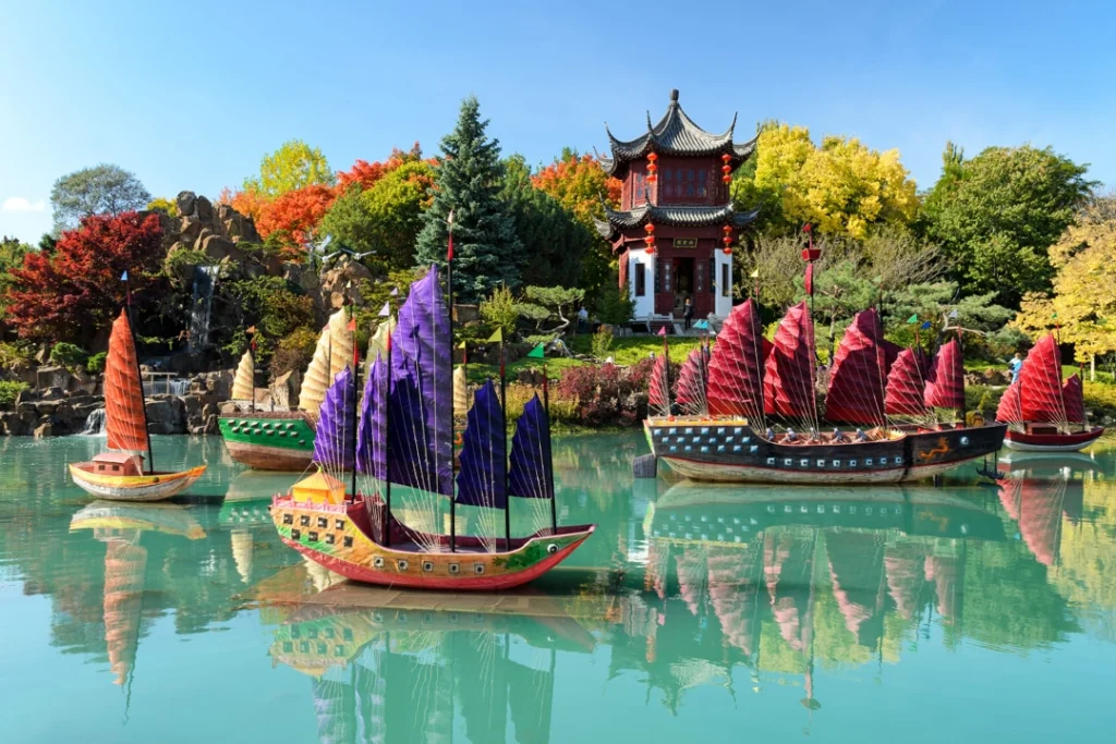 Kleurrijke traditionele sierboten met gekleurde zeilen drijven op het water bij een pagode in de Chinese tuin van Montréal
