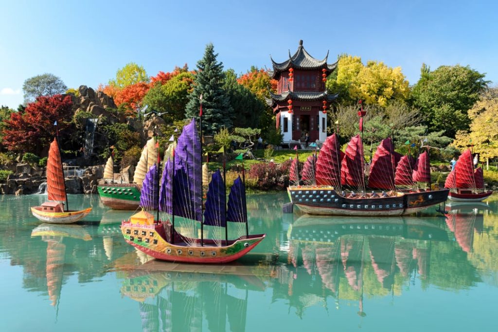 Kleurrijke traditionele Chinese jonken met gekleurde zeilen liggen op het water bij een pagode in de Chinese tuin van Montreal