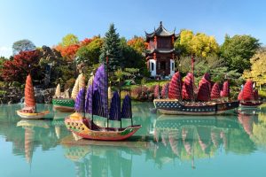 Kleurrijke traditionele Chinese jonken met gekleurde zeilen liggen op het water bij een pagode in de Chinese tuin van Montreal