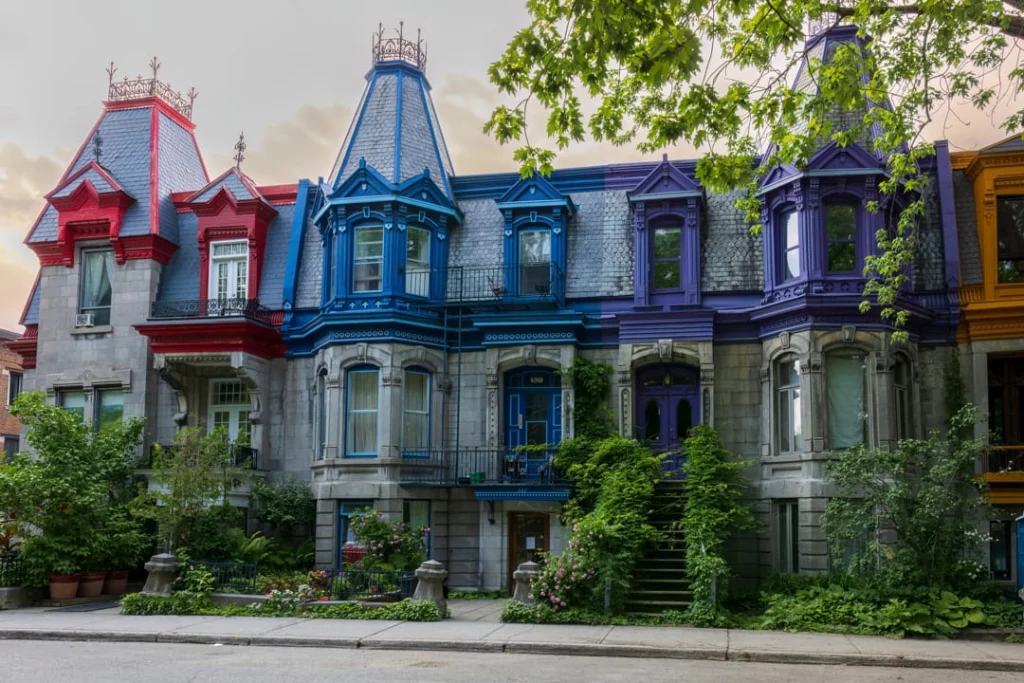 Rij Victoriaanse stadshuizen met puntdaken in felle kleuren zoals rood, blauw en paars, met groen voor de gevels