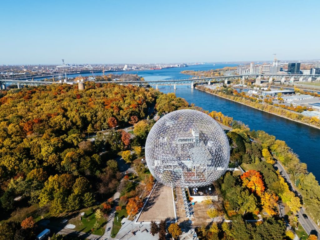 Wit reuzenrad tussen felrode herfstbomen, weerspiegeld in het rustige water van de oude haven van Montreal