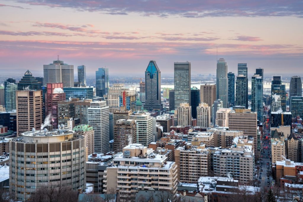 Wolkenkrabbers van het centrum van Montreal met een roze en paarse avondlucht, gezien vanaf de uitkijk op Mont Royal
