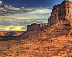 Hoog rotsplateau met steile wanden en een lager gelegen mesa in de rode woestijn van Monument Valley bij avondlicht