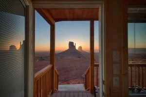Uitzicht door een houten deuropening op de rotsformaties van Monument Valley bij zonsondergang