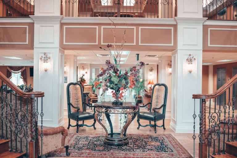 Elegante hotellobby in Muscle Shoals met een dubbele sierlijke trap, twee antieke stoelen en een grote bloemarrangement op een ronde tafel
