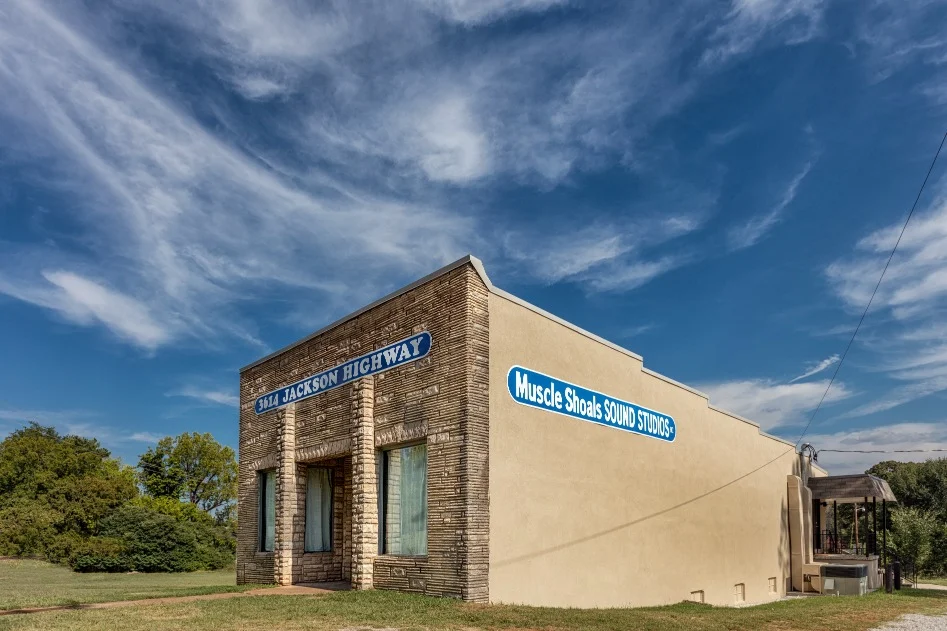 Laag gebouw van steen en pleisterwerk met het bord Muscle Shoals Sound Studios aan Jackson Highway onder een blauwe lucht met sluierwolken