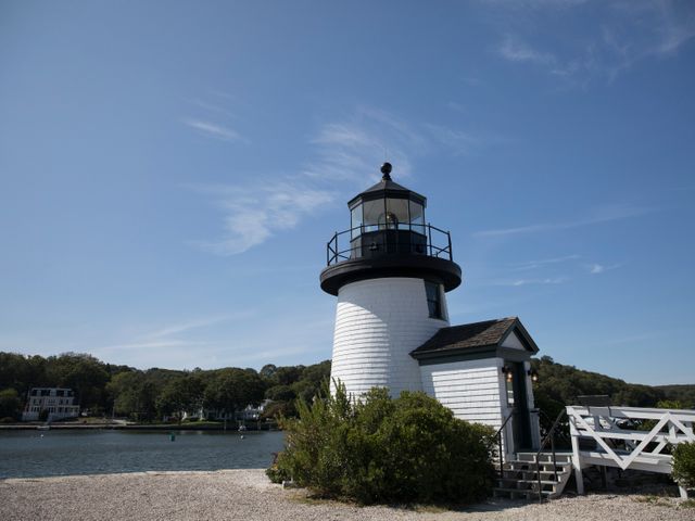Kleine witte vuurtoren met zwarte lantaarnruimte naast een houten hek bij het water van Mystic Seaport in Connecticut