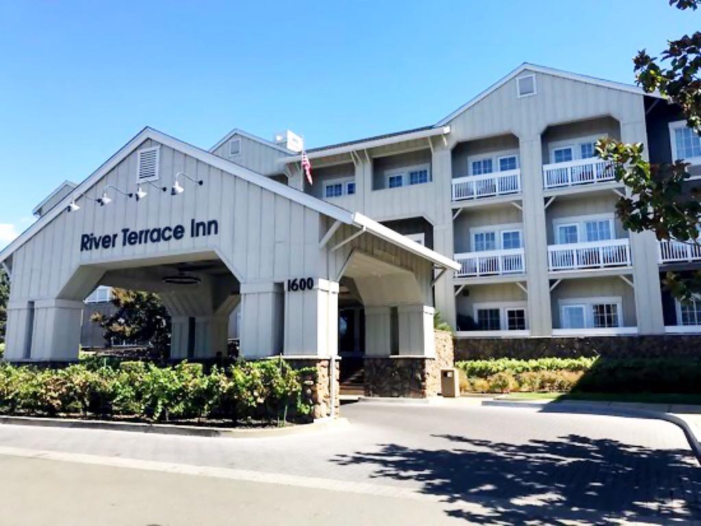 Ingang van hotel River Terrace Inn met een houten luifel, vlaggenmast en parkeerplaats ervoor in Napa