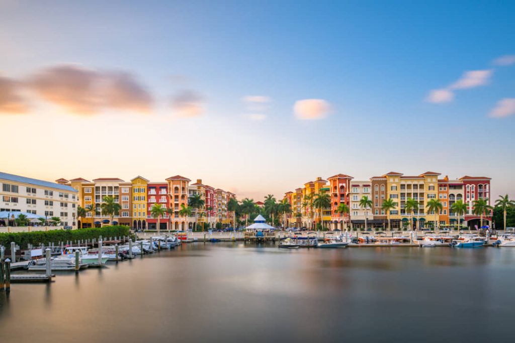 Jachthaven met aangemeerde boten voor rijen kleurrijke gebouwen in mediterrane stijl in Naples in Florida bij schemering