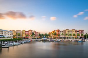 Jachthaven met aangemeerde boten voor rijen kleurrijke gebouwen in mediterrane stijl in Naples in Florida bij schemering