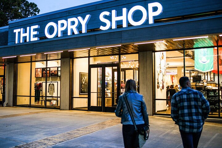 Bezoekers lopen naar de verlichte etalages van de Opry Shop in de avondschemering in Nashville