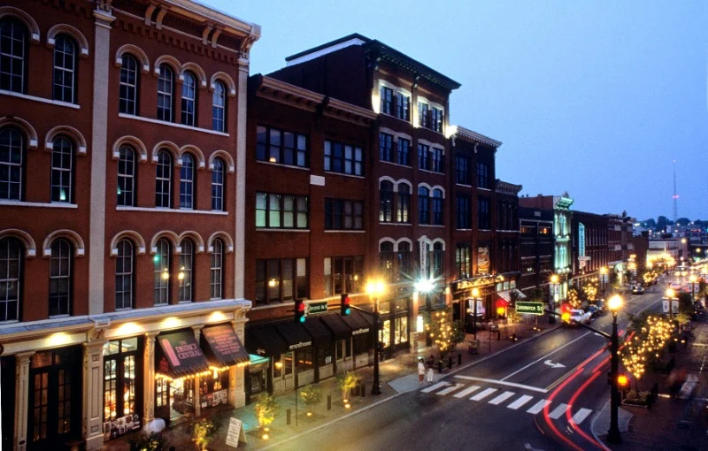 Verlichte historische bakstenen gebouwen langs een straat in downtown Nashville bij avondschemering met lichtsporen van auto's