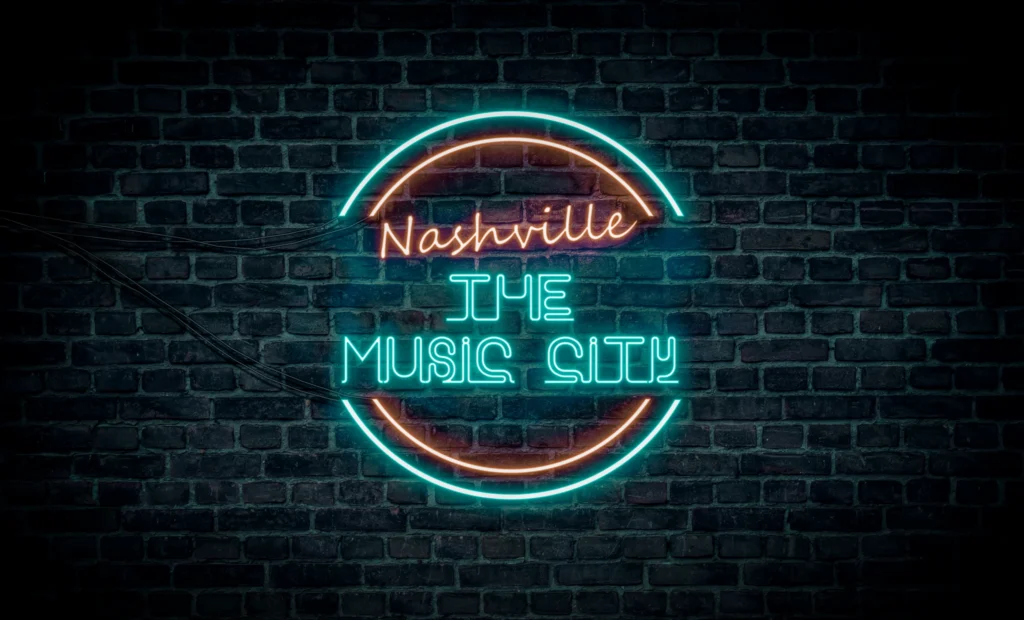 Blauw en roze neonbord met de tekst Nashville the Music City tegen een donkere bakstenen muur