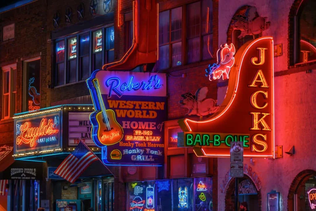 Felgekleurde neonreclames van countrybars en restaurants verlichten de gevels langs Broadway in Nashville in de avond