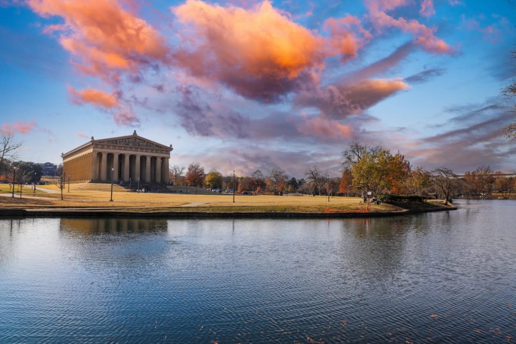 Replica van het Griekse Parthenon in Centennial Park Nashville met een roze bewolkte lucht weerspiegeld in het meer ervoor