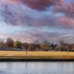 Volledige replica van het Griekse Parthenon met zuilen weerspiegeld in het water in Nashville onder een kleurrijke avondlucht