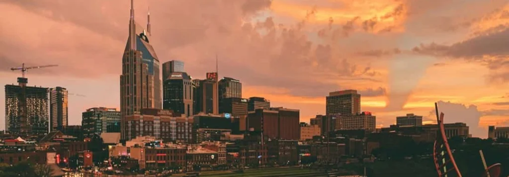 De skyline van Nashville met de opvallende torenspitsen van het AT&T gebouw kleurt oranje tegen een dramatische wolkenlucht bij zonsondergang