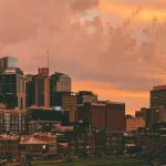De skyline van Nashville met de opvallende torenspitsen van het AT&T gebouw kleurt oranje tegen een dramatische wolkenlucht bij zonsondergang