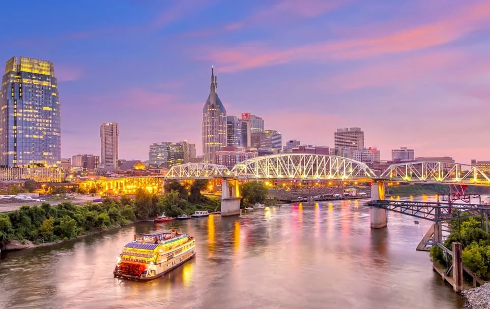Zonsondergang boven de skyline van Nashville met een verlichte rivierboot en brug over de Cumberland River