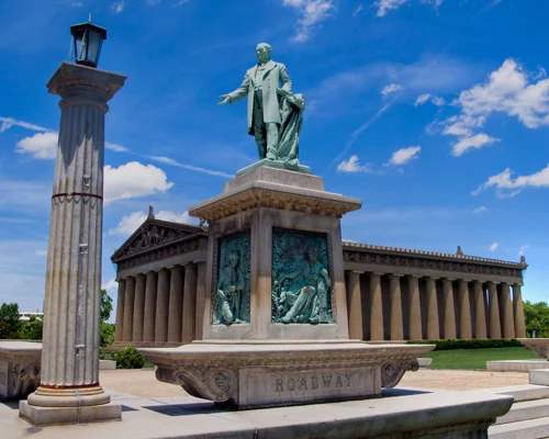 Bronzen standbeeld van een man op een sokkel met een lantaarnpaal en de zuilengalerij van het Parthenon op de achtergrond in Nashville
