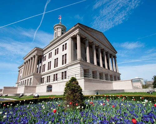 Het classicistische Tennessee State Capitol met zuilen en een torentje, met een perk vol rode en blauwe tulpen op de voorgrond