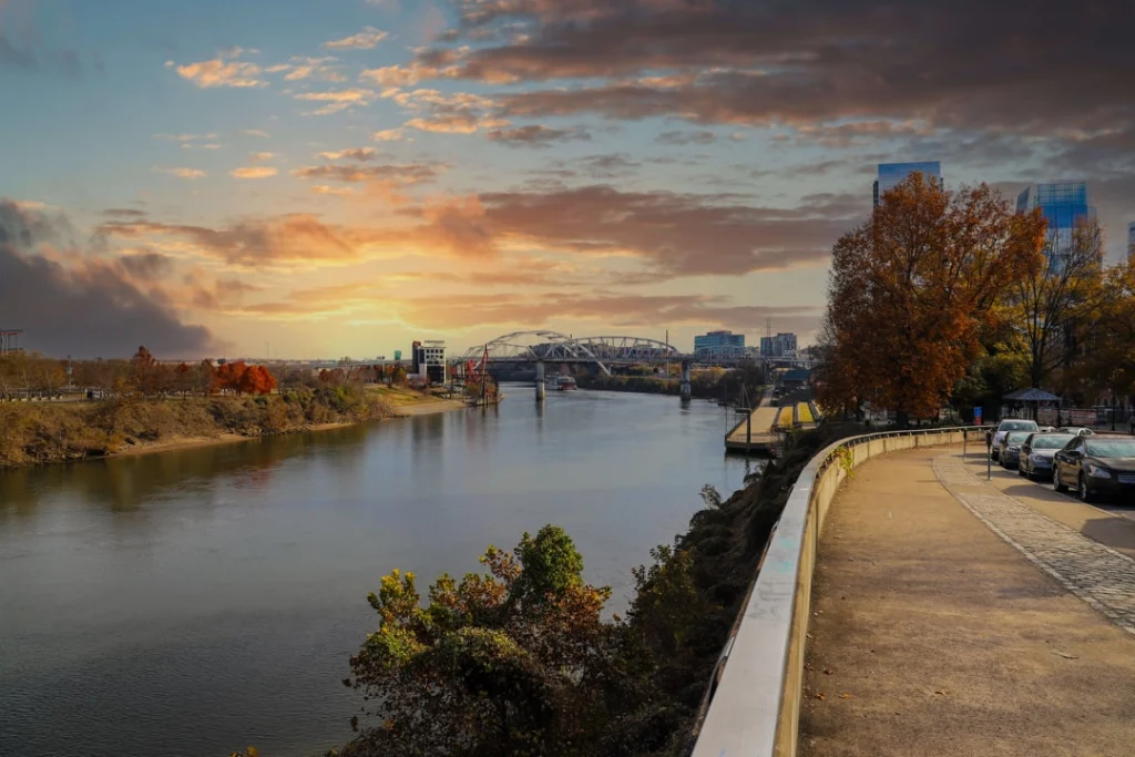 Wandelpad langs de Cumberland rivier met een brug op de achtergrond en bomen in oranje herfstkleuren in Nashville bij zonsopgang