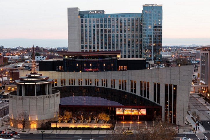 Modern gebouw van de Country Music Hall of Fame met een torenspits en een hotel op de achtergrond in Nashville bij het invallen van de avond