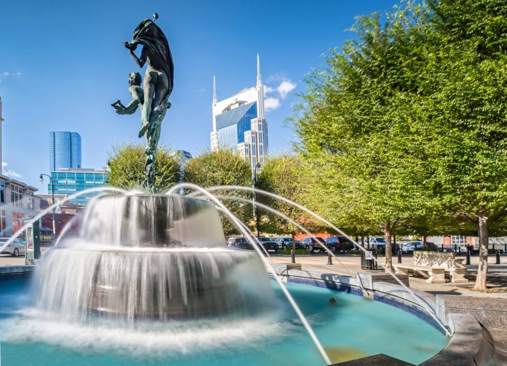Bronzen dansende figuren op een fontein op een rotonde in Nashville, met de torenspitsen van het AT&T gebouw op de achtergrond