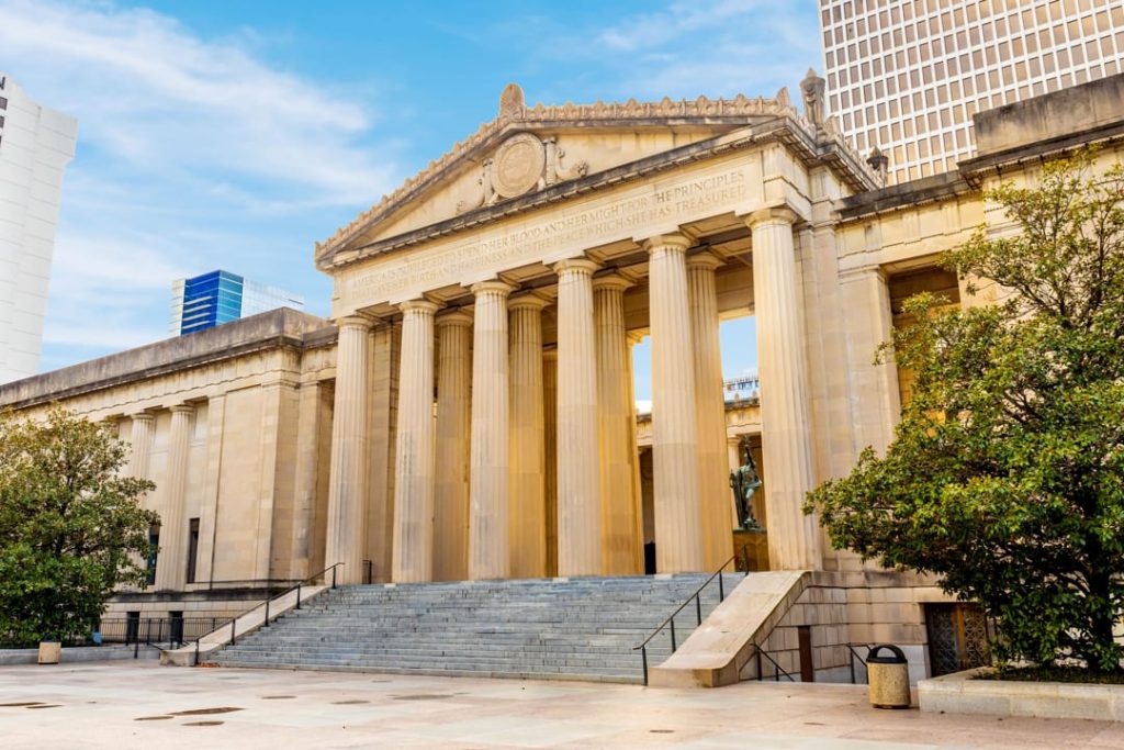 Gevel met een rij hoge zuilen en een fries met tekst van het War Memorial Building in Nashville tegen een blauwe lucht