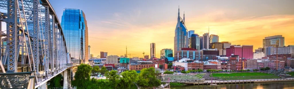Skyline van Nashville met de kenmerkende torenspitsen van het AT&T gebouw, gezien vanaf de historische stalen voetgangersbrug over de Cumberland rivier