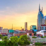 Skyline van Nashville met de kenmerkende torenspitsen van het AT&T gebouw, gezien vanaf de historische stalen voetgangersbrug over de Cumberland rivier