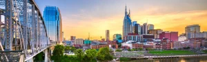 Skyline van Nashville met de kenmerkende torenspitsen van het AT&T gebouw, gezien vanaf de historische stalen voetgangersbrug over de Cumberland rivier