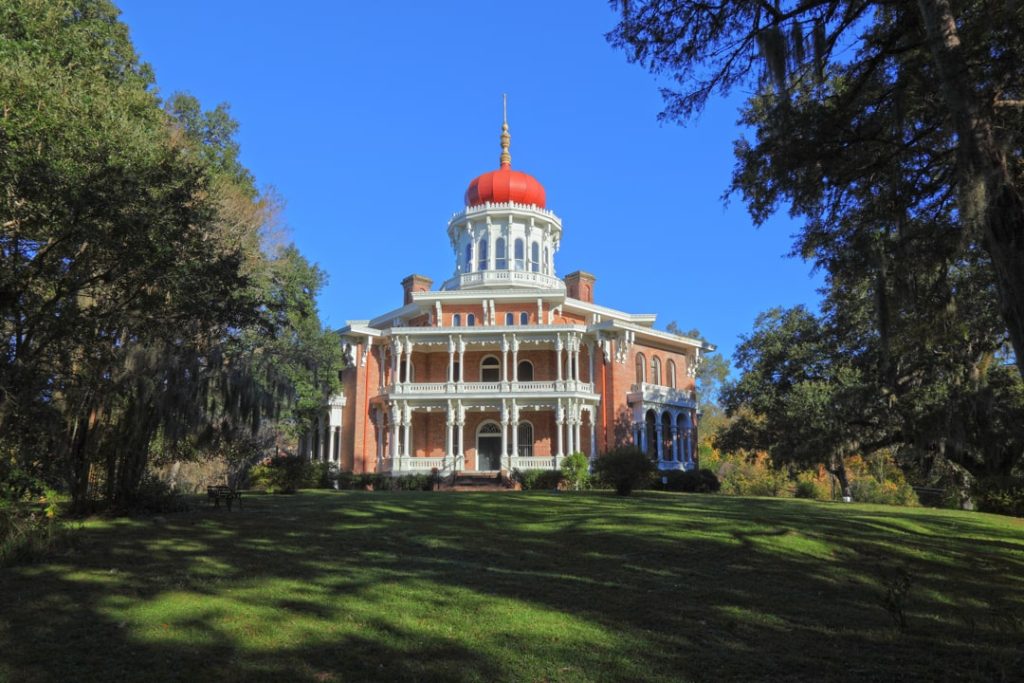 Roze bakstenen octagonale villa met wit houtwerk en een opvallende rode koepel omringd door bomen met spaanse mos in Natchez