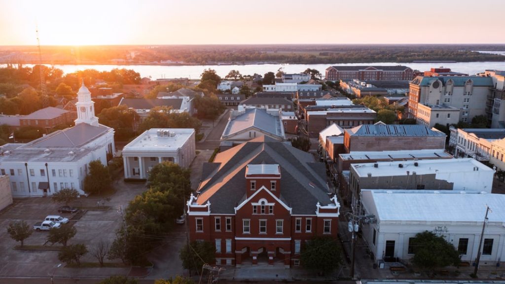Luchtfoto van de historische gebouwen en kerktorens van Natchez met de Mississippi rivier op de achtergrond bij zonsondergang